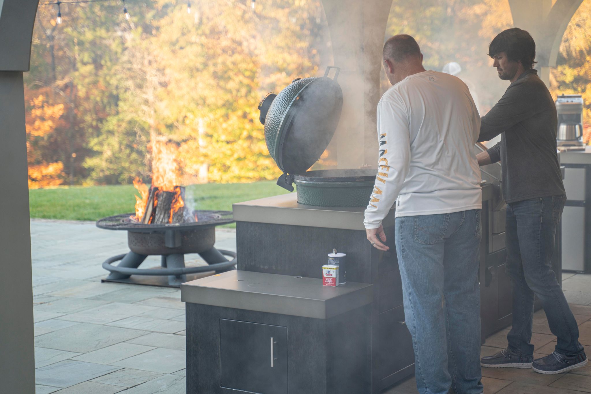 A man grills meat on his grill cart by Stoll Industries as part of his outdoor kitchen.