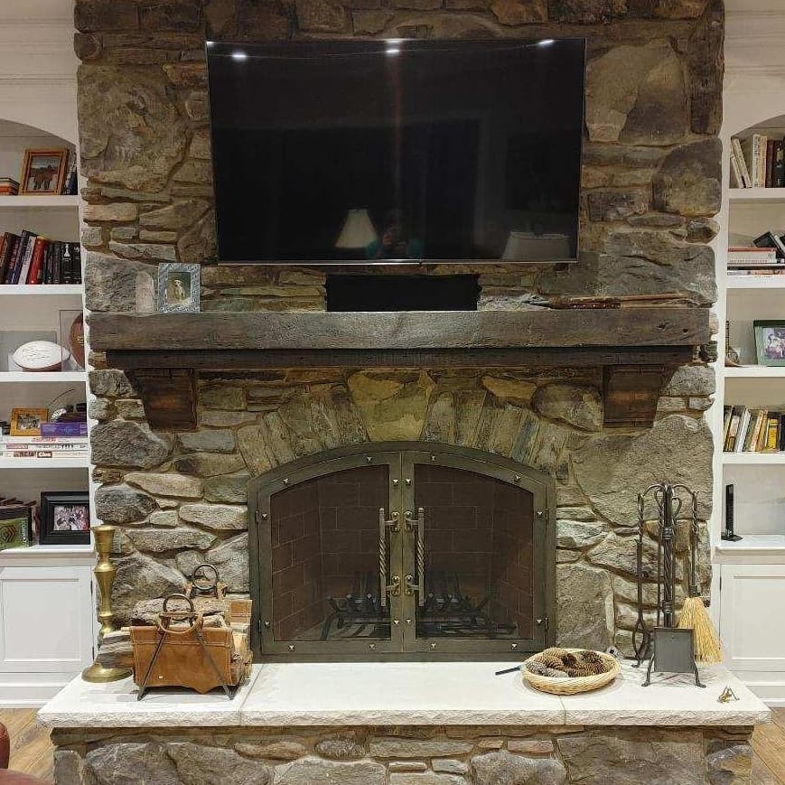 A stone fireplace Featuring Stoll Fireplace Doors