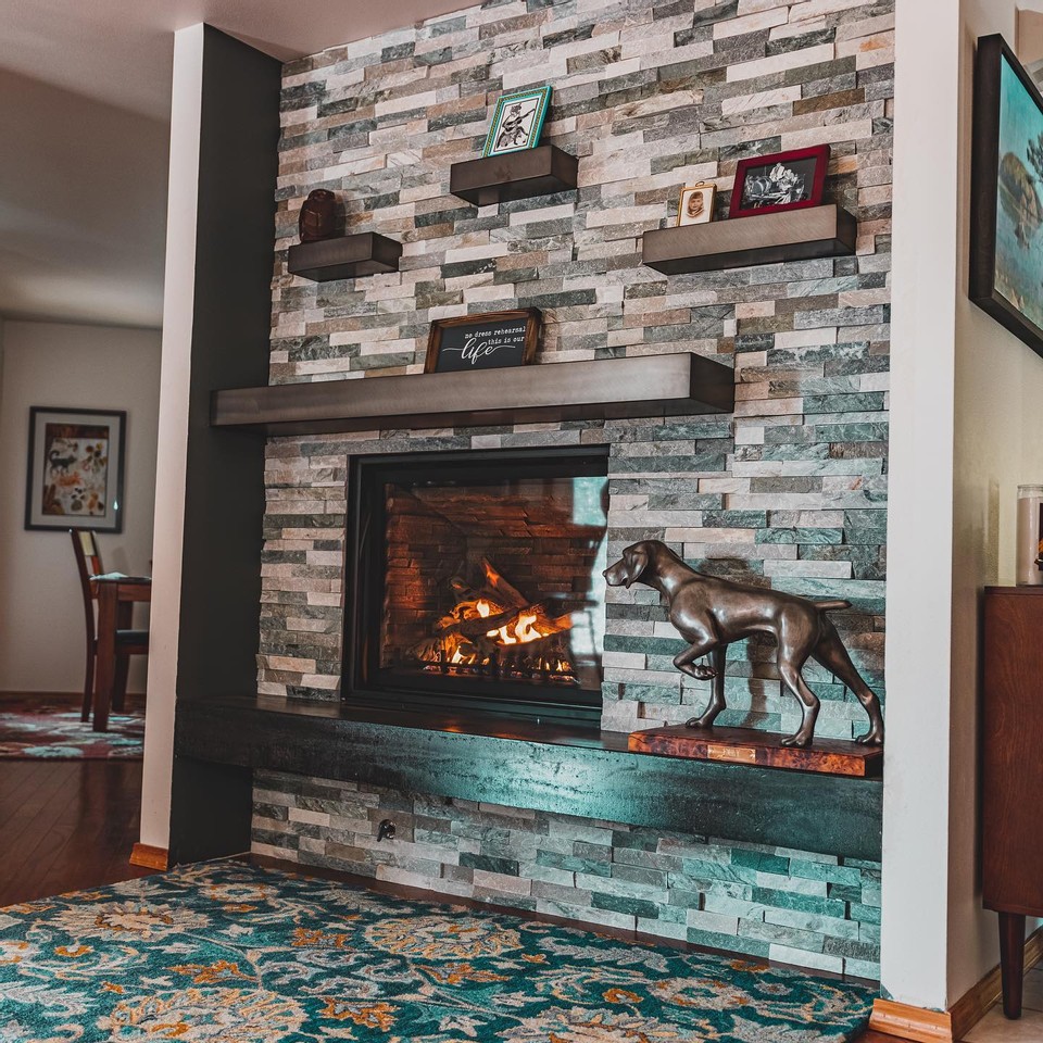 A stone fireplace with floating shelves in a home remodel.
