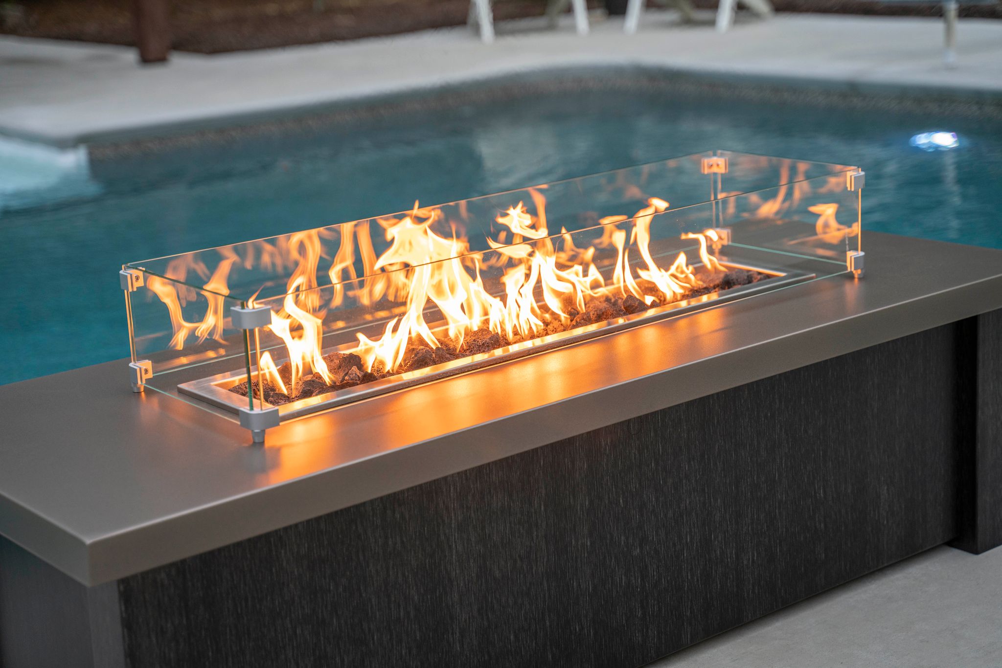 A close up of a Stoll Industries fire table with a wind shield and custom finishes.