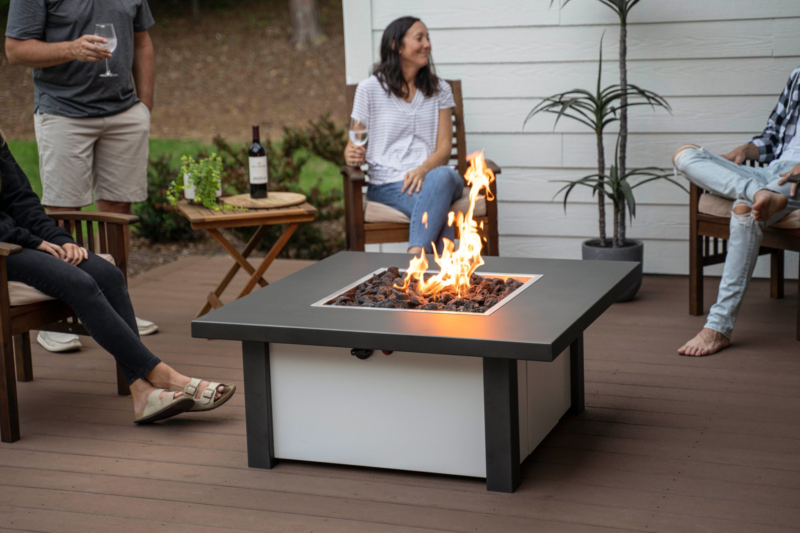A family sits around a fire pit table by Stoll Industries.